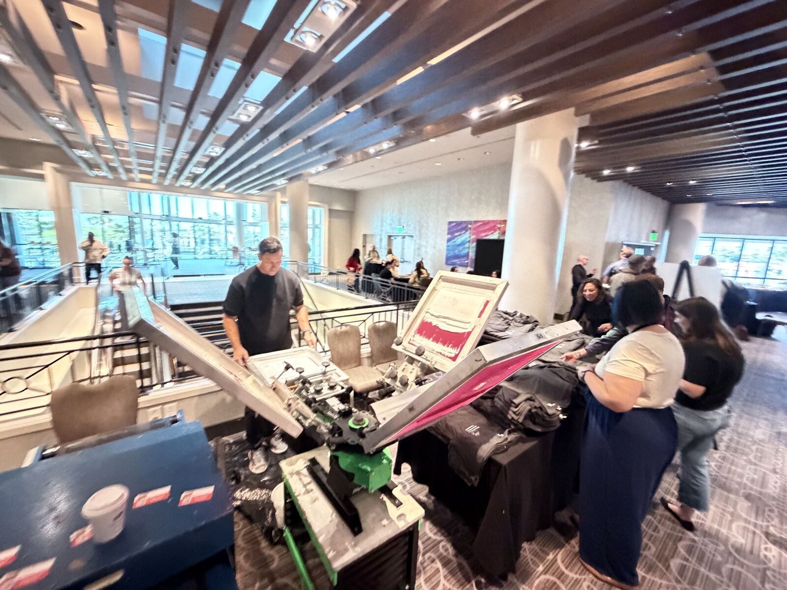 Live printing station at a corporate event with an operator running the press and finished custom apparel for guests